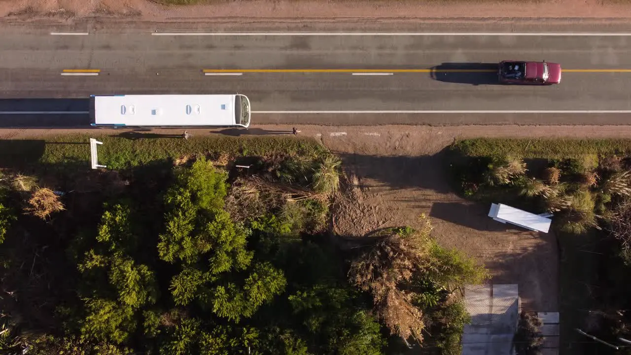 Aerial top down shot of passenger leaving bus at bus station during cars overtaking at sunset Punta del Este Uruguay