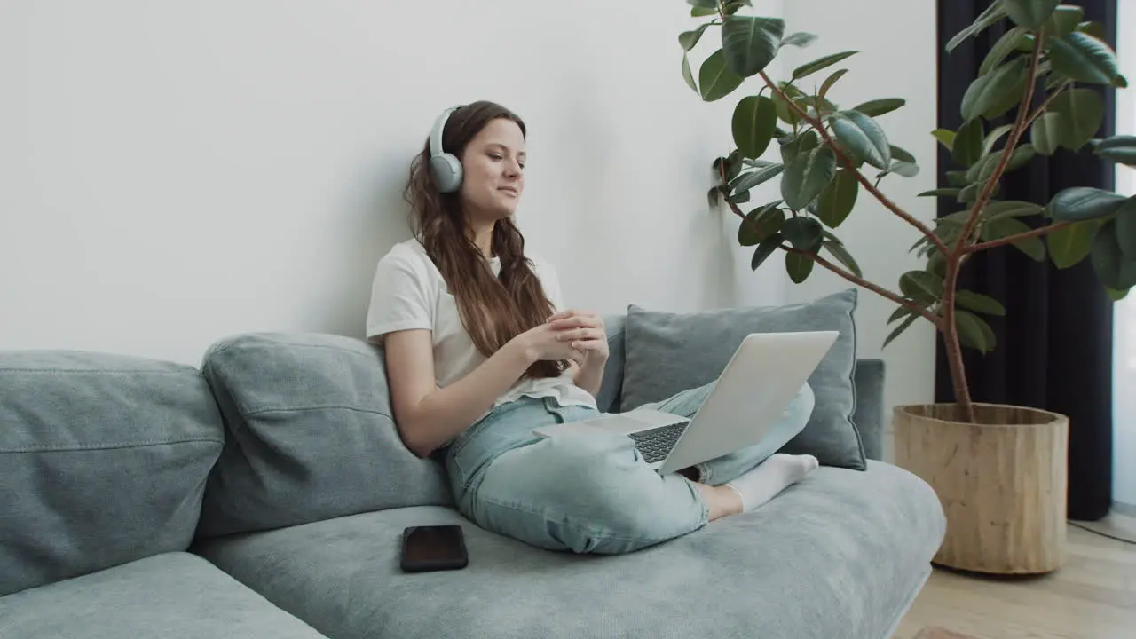 Cute Young Female Makes A Video Call With Her Laptop From The Sofa At Home 1