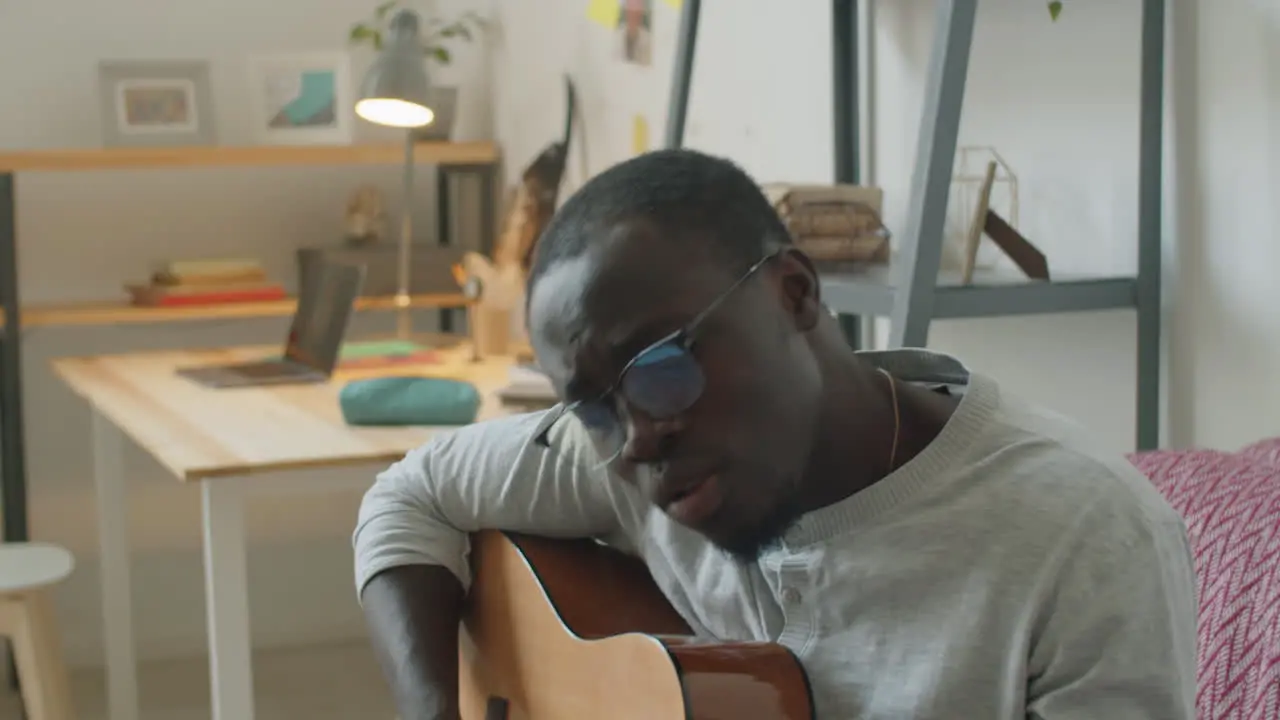 Black Man Singing and Playing Guitar at Home