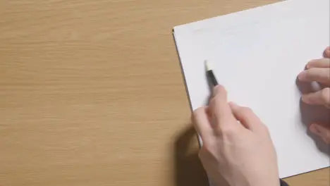 Person Sketching With Pencil On Pad On Wooden Table Background