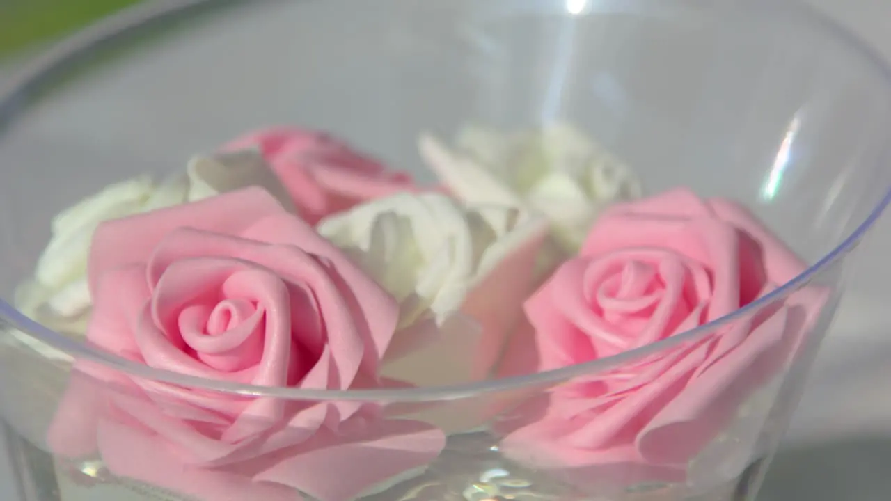 Pink carnation flowers roses floating in water in clear bowl