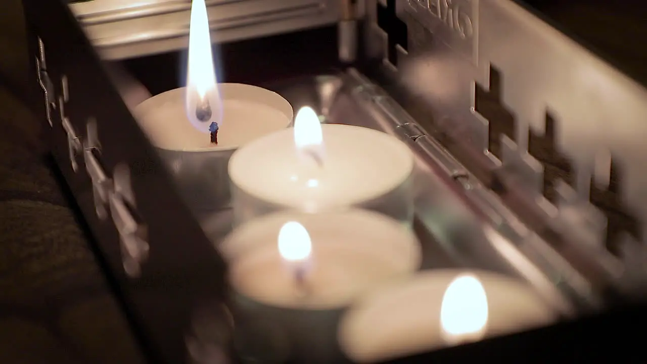 Close up lighting up small candles in metal container with match stick