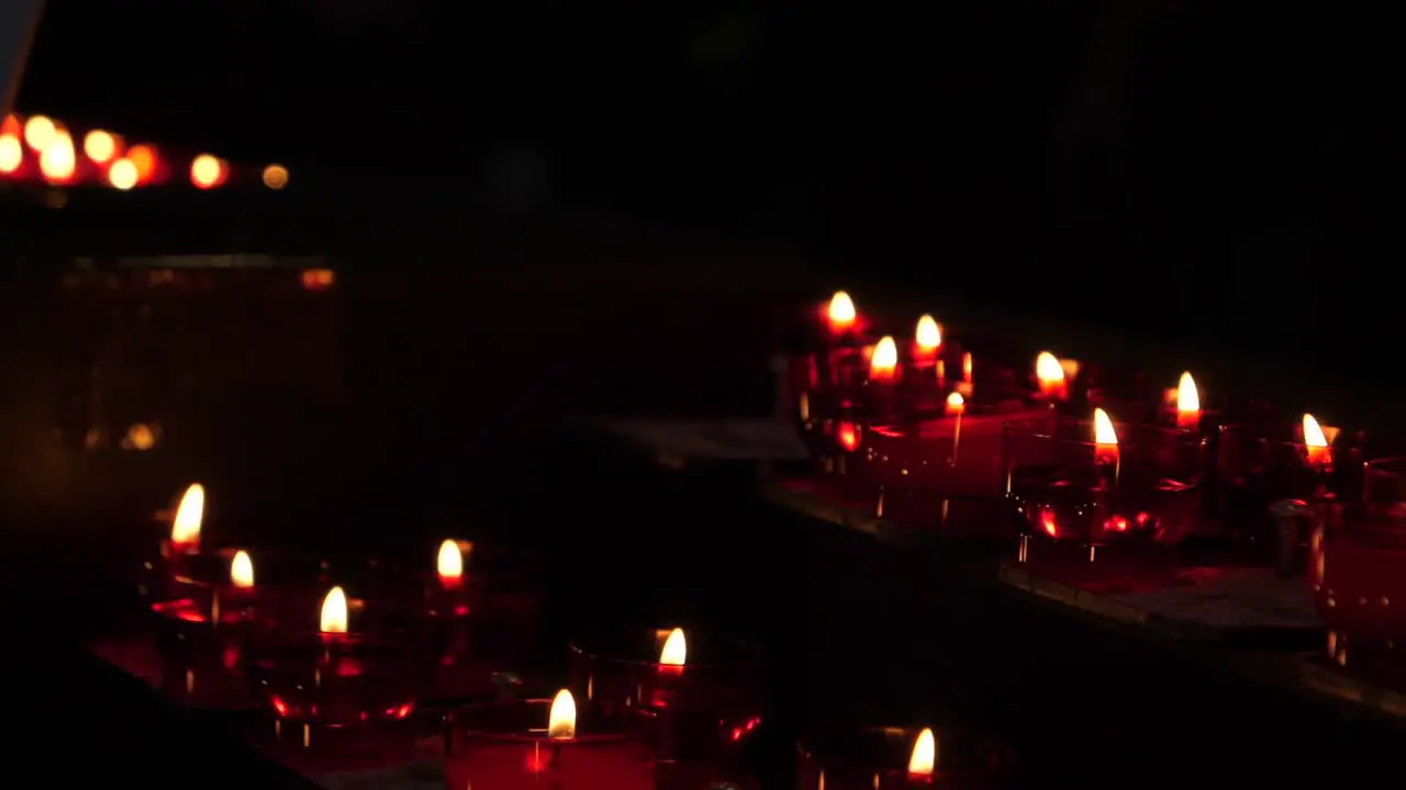 Moody slow motion shot of multiple glowing candles burning in holy chapel