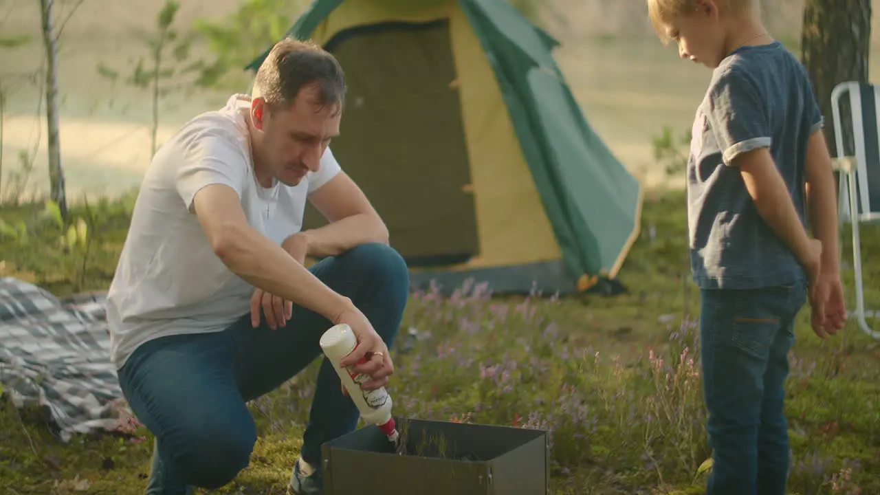 father and son are inflaming coals in chargrill picnic and rest at nature family trip in forest and stay in tent camp