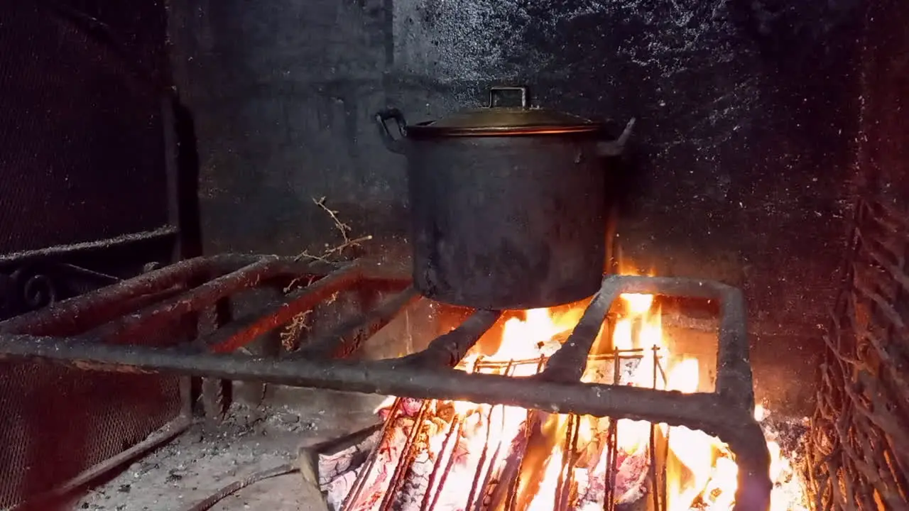 Food cooked in black pot made on fire bonfire and black walls of fire