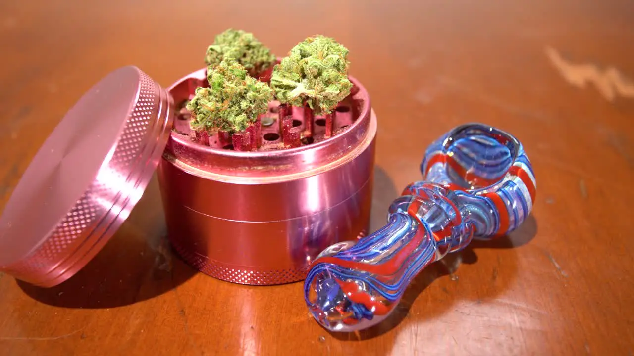 Pan across grinder full of cannabis next to pipe