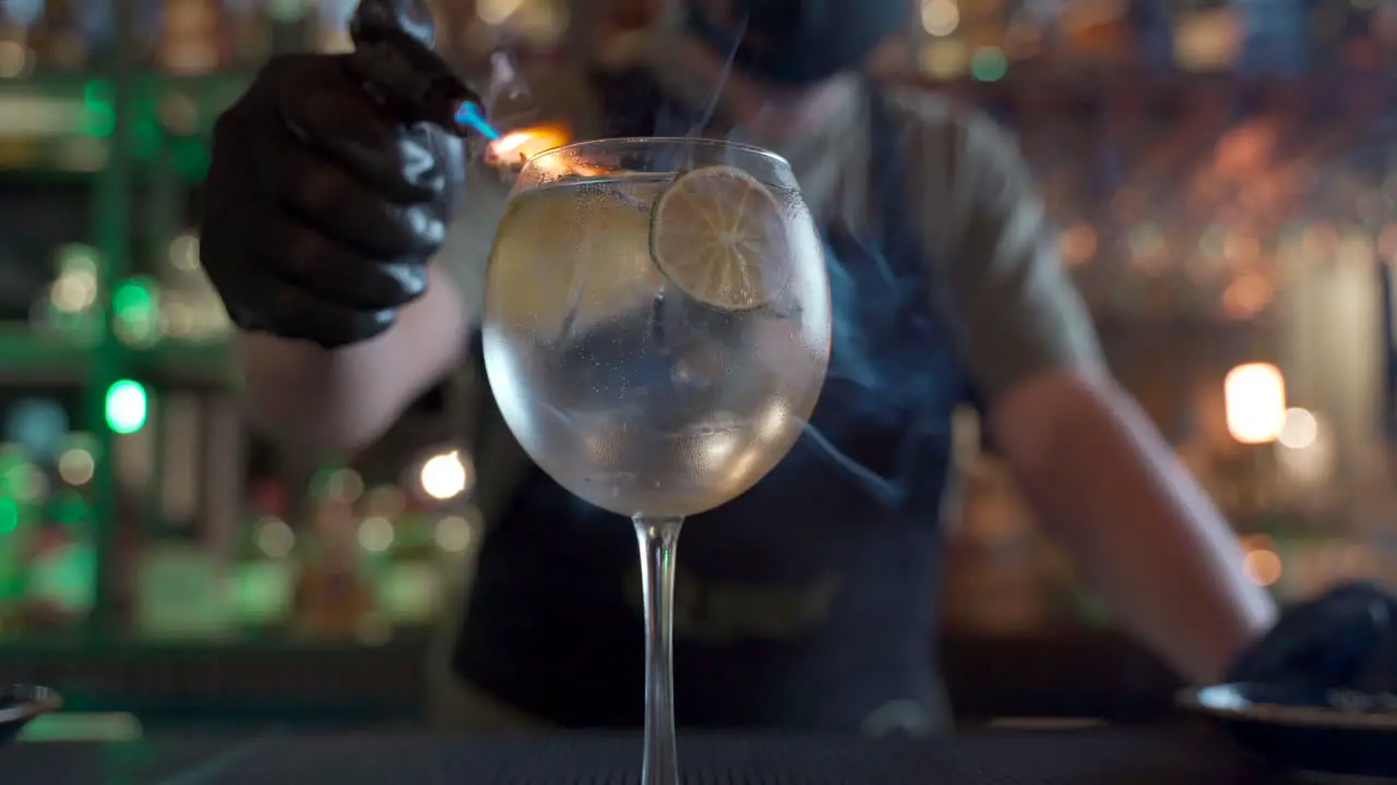 latin bartender smoking citrus vodka tonic flaming blurry bar background