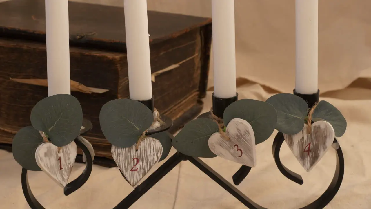 Slow tilt up of four numbered lit candles by old heavy book close-up