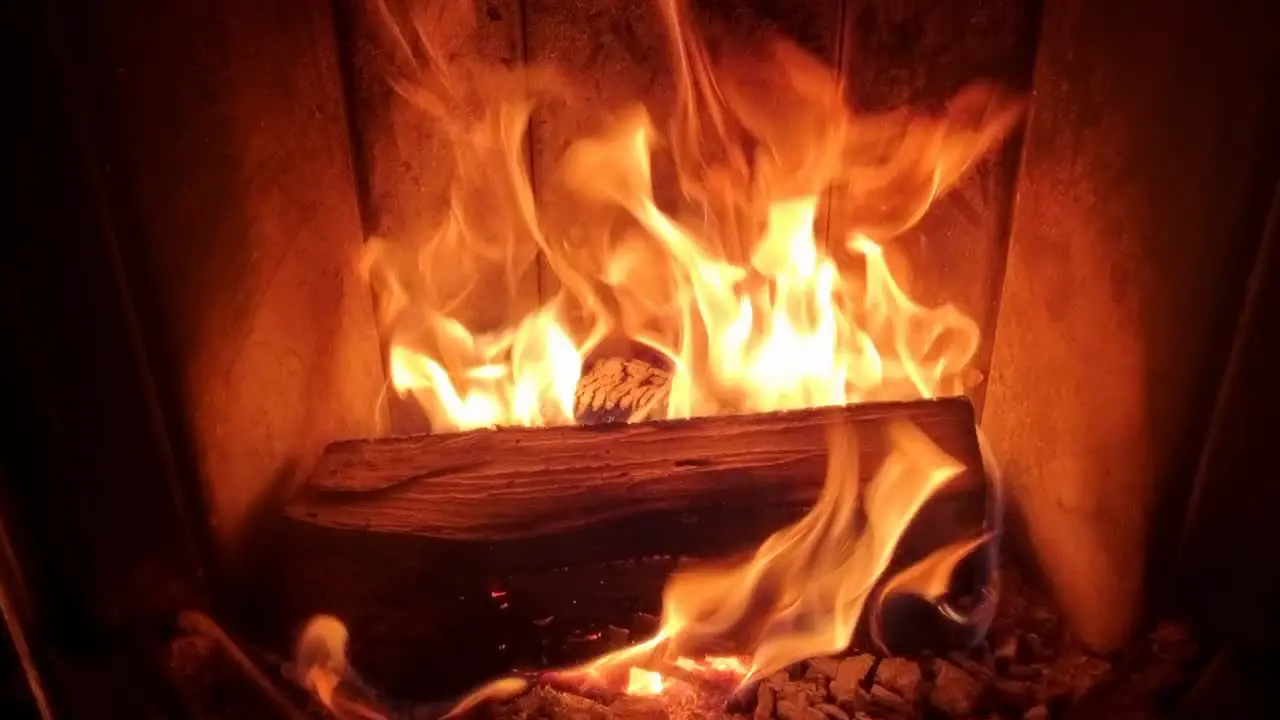 Wood burning fireplace in home with large burning hot orange bright flames providing heat to home with fire during winter time