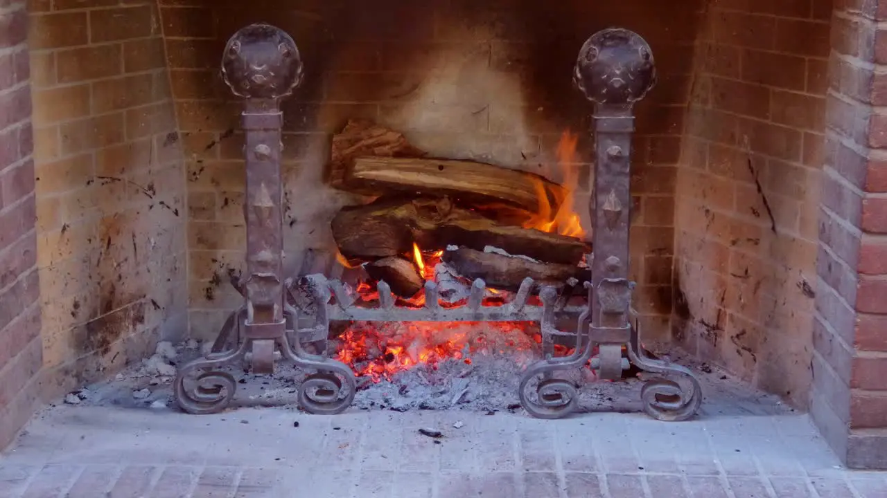 Close up of a log fire burning in a old style fireplace with a warm glow form the coals and ash