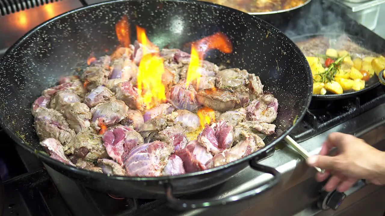 Close up of person cooking a delicious stew in the pan while a flame is coming out