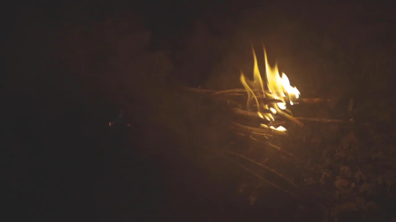 Slider motion shot of a small pile of sticks burning in a fire pit