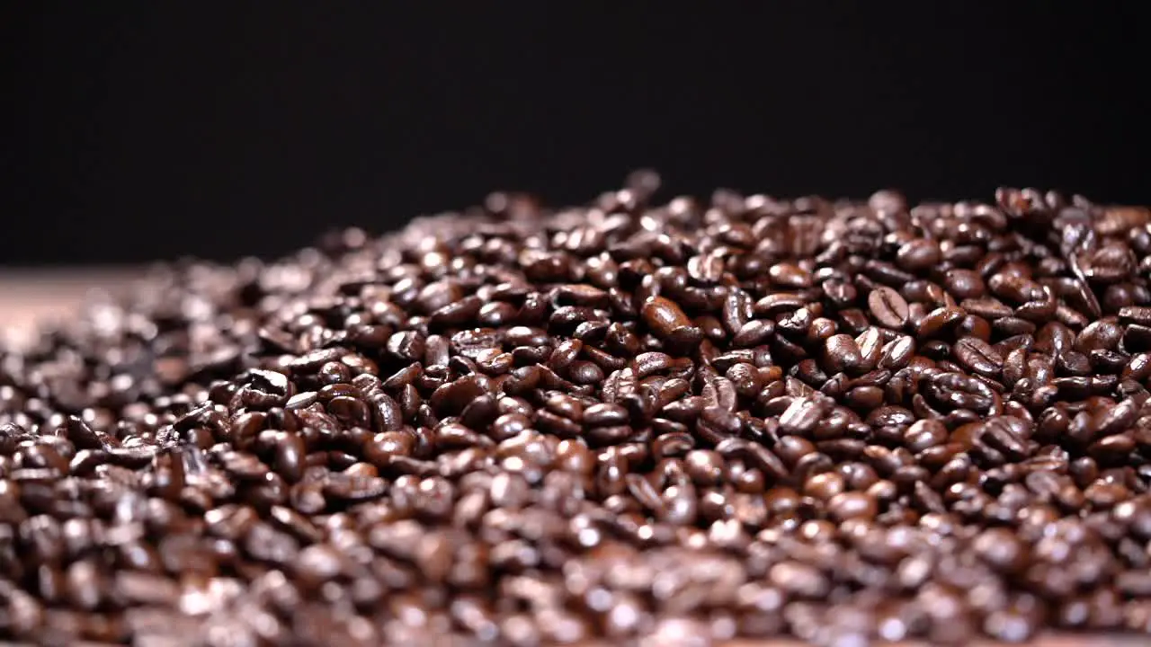 Coffee beans falling in a pile HD Slow motion on black background