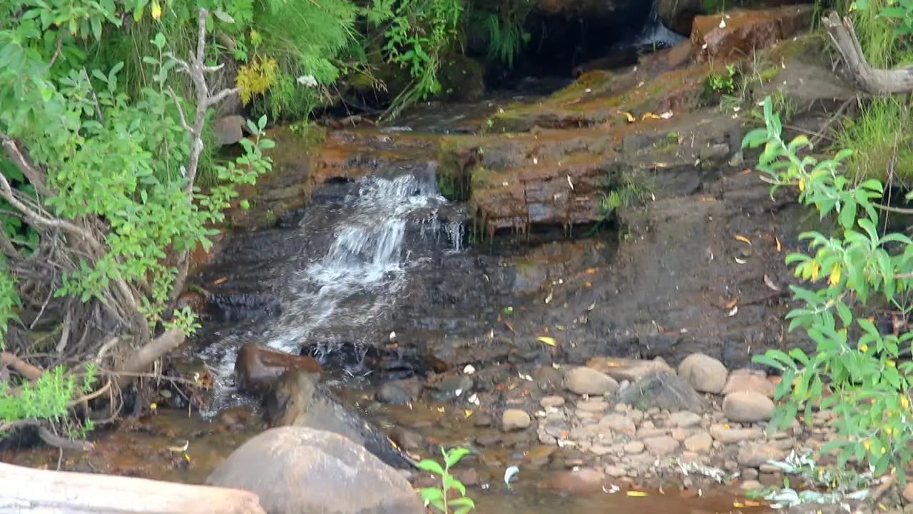 Waterfall from a stream flowing over rocks creating a small waterfall on beach in Kenai Peninsula of Alaska