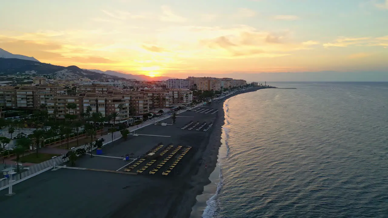 Aerial drone forward moving shot over beautiful beach front along the coastal town of Fuengirola in Malaga Spain at sunrise