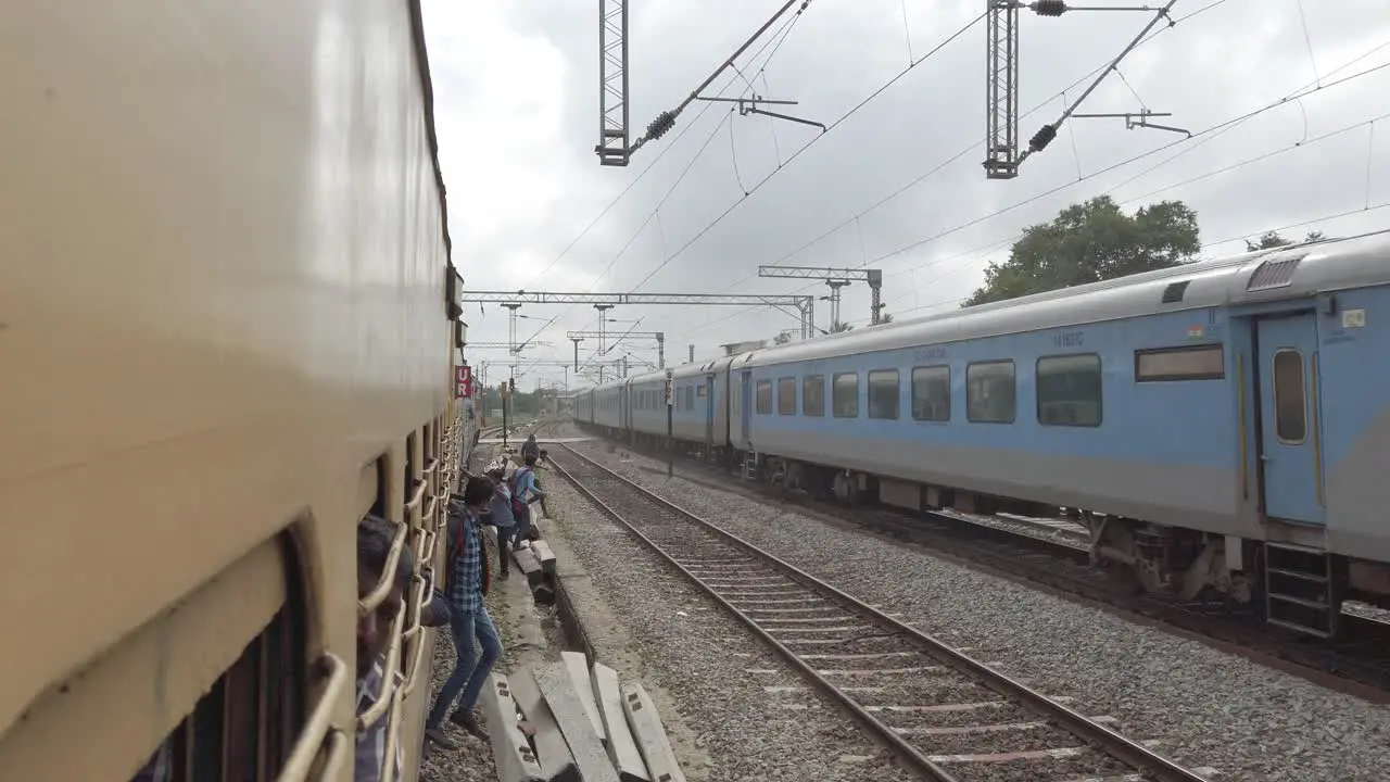 Vaniyambadi Tamilnadu India December 14 2019 People jumping from an electric train and dangerously crossing the tracks while another train passes at high speed in the opposite side