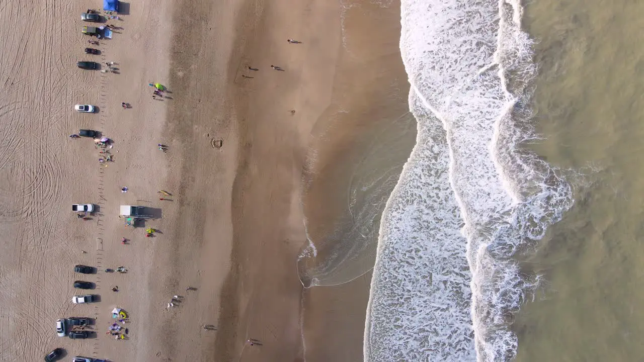 Static top down drone shot of a beach in Cariló Argentina with waves crashing on the shore