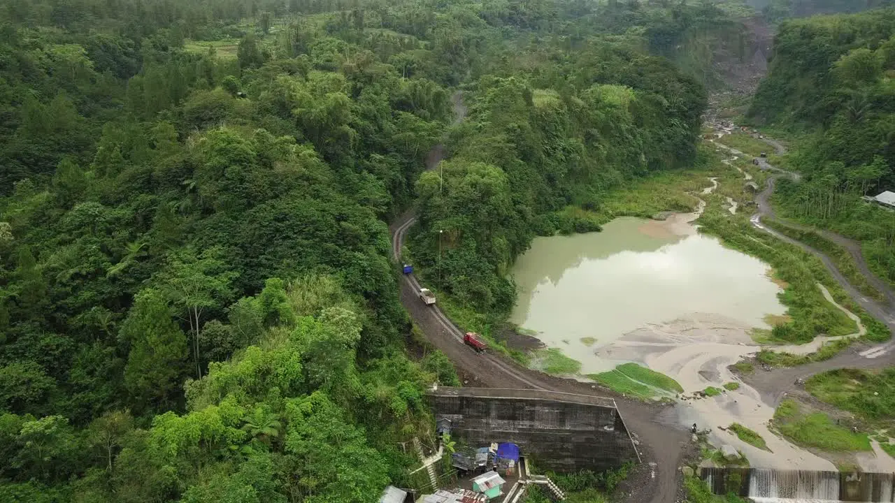 the trucks move on the road between the dense forest on the slopes of Mount Merapi to the sand mines