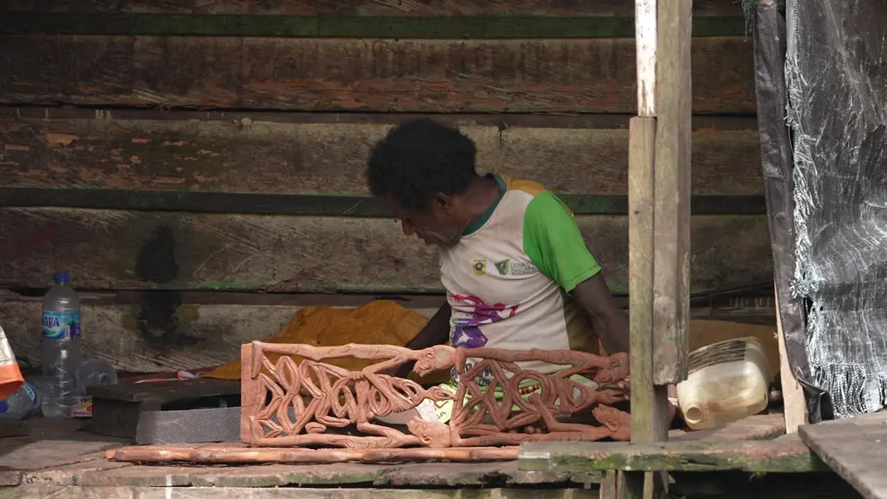 The old man is working on making typical Asmat wood carvings that are sought after by many collectors