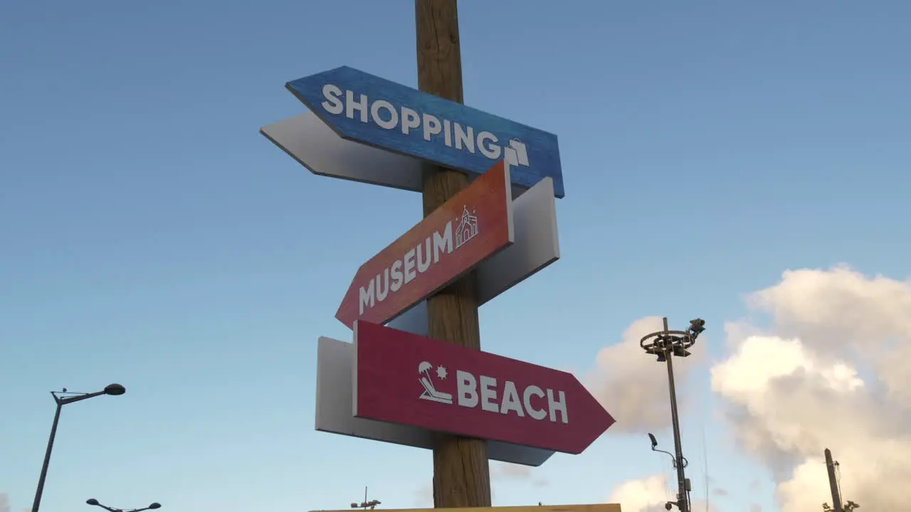 Different signs pointing at beach shopping and museum at daylight and blue sky