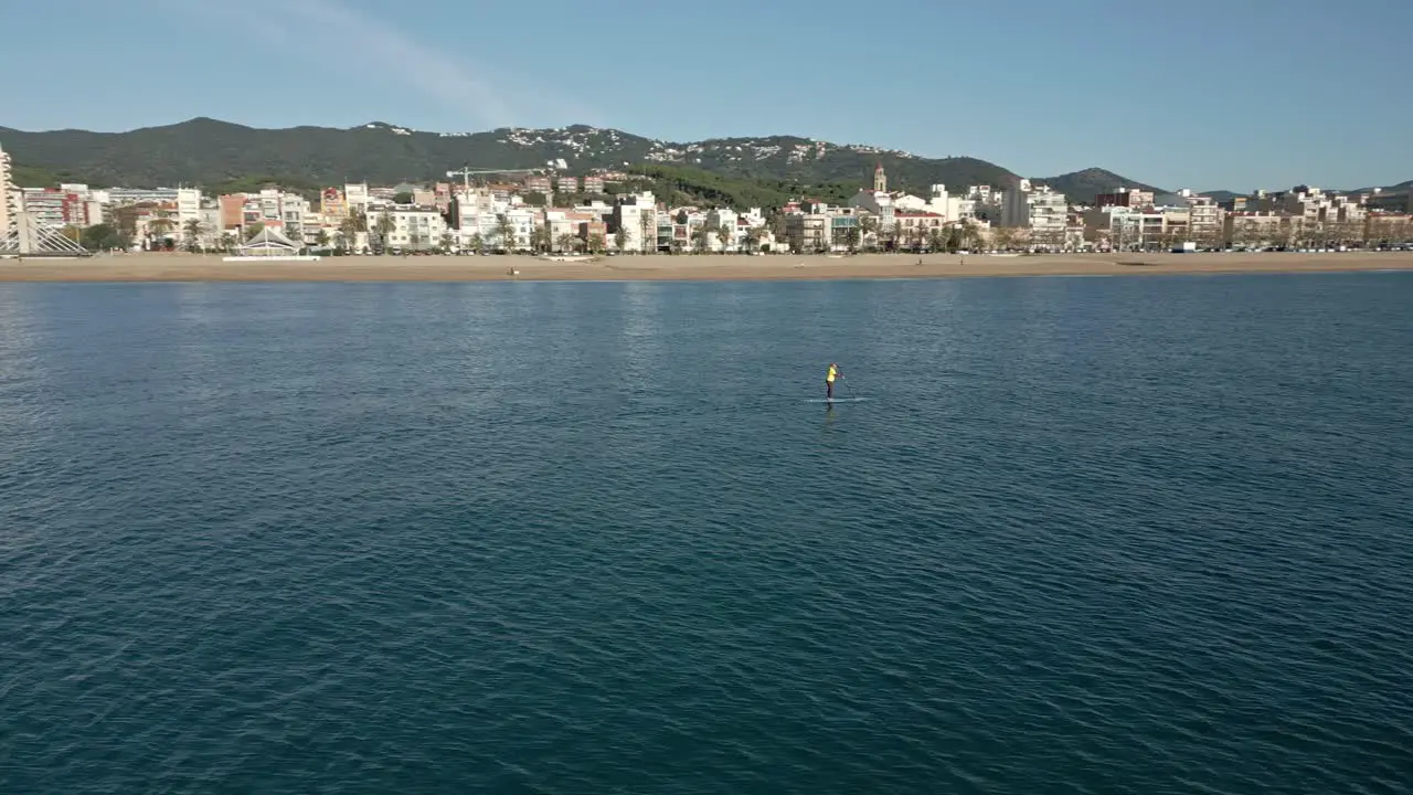 Orbits over a solo stand-up paddle surf with a view of the town in the background on a sunny autumn day