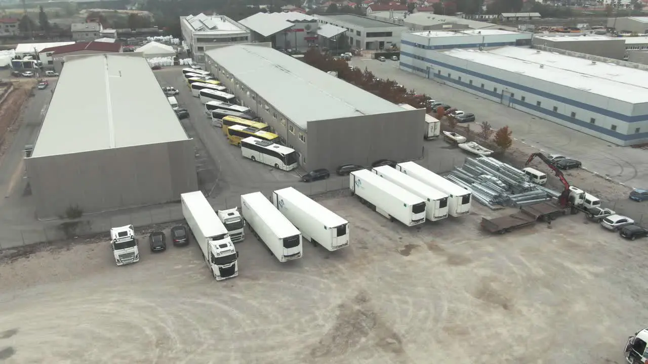 An industrial zone with lost of truck and busses parked next to some industrial buildings halls