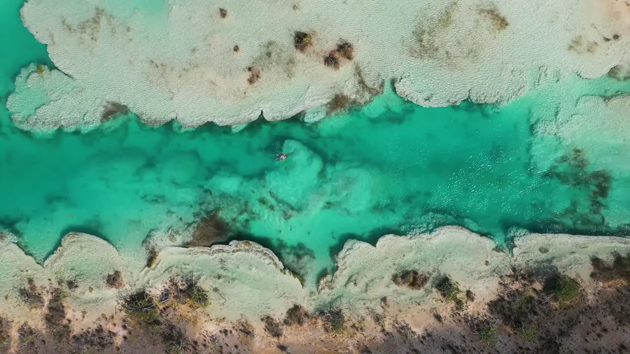 Man bathing in hot spring river rapids of Bacalar in Mexico 4K aerial top down