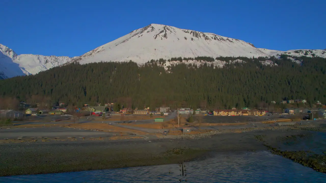 Sideways flyover view of Seward Alaska and mountains at sunrise