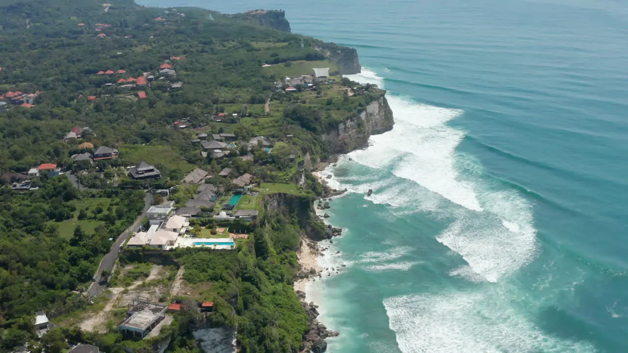 Luxury tropical villas and holiday homes with pools on top of the cliff above turquoise blue sea in Bali Indonesia