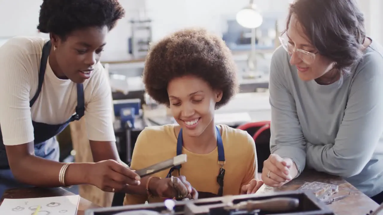 Busy diverse female workers shaping ring with handcraft tools in studio in slow motion