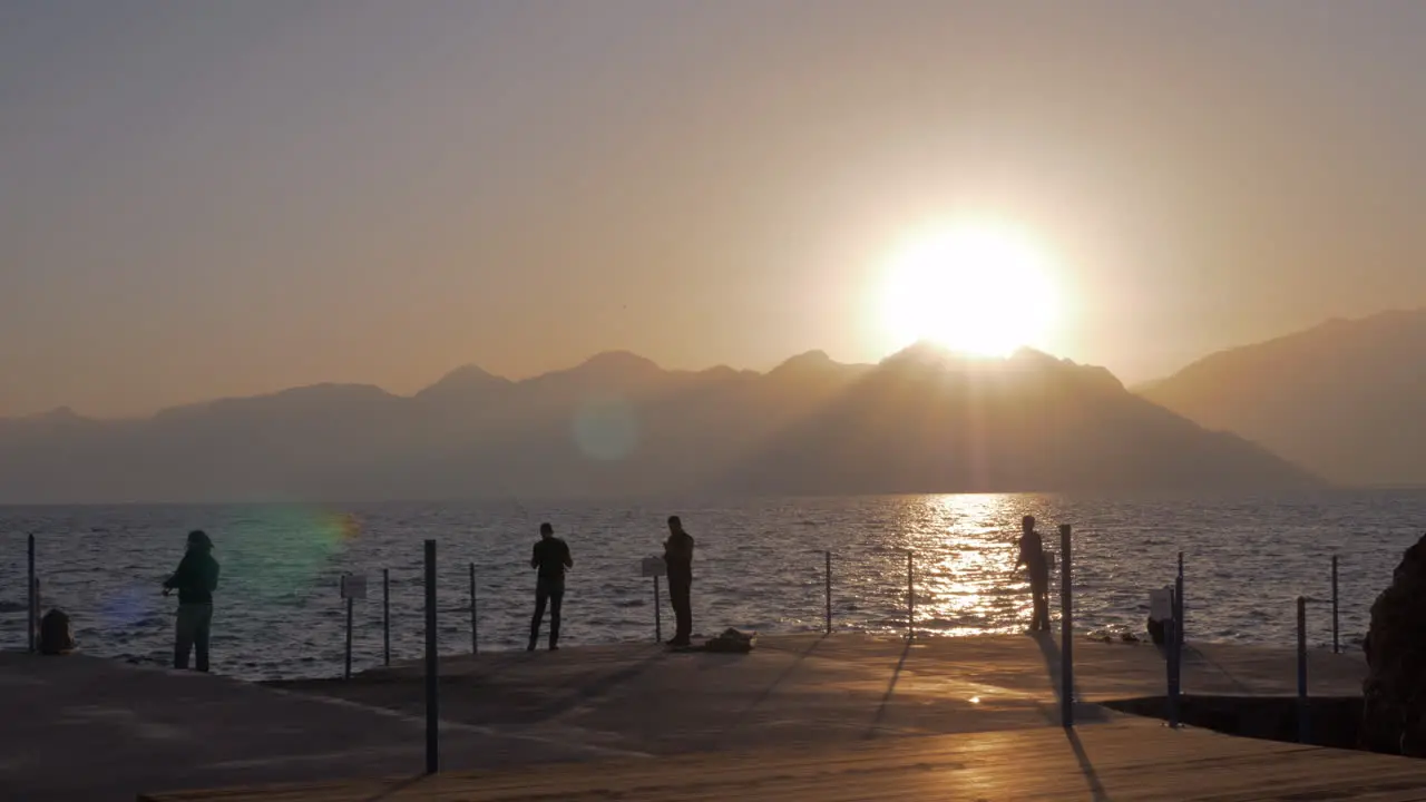 Men fishing on the pier at sunset