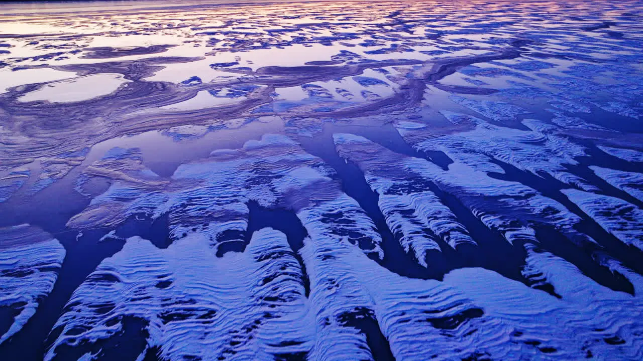 Drone's perspective as it reveals the grandeur of ice masses on the water during a cold sunrise