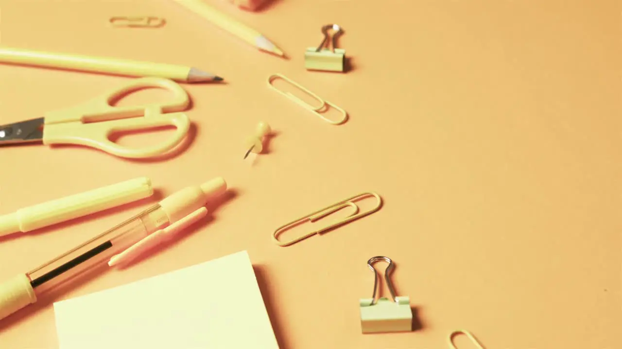 Close up of school stationery on orange background in slow motion