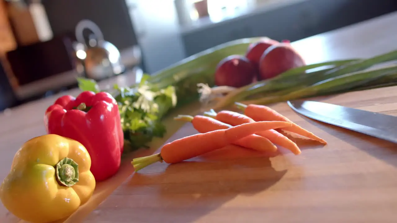 Organic vegetables and knife on countertop in sunny kitchen slow motion