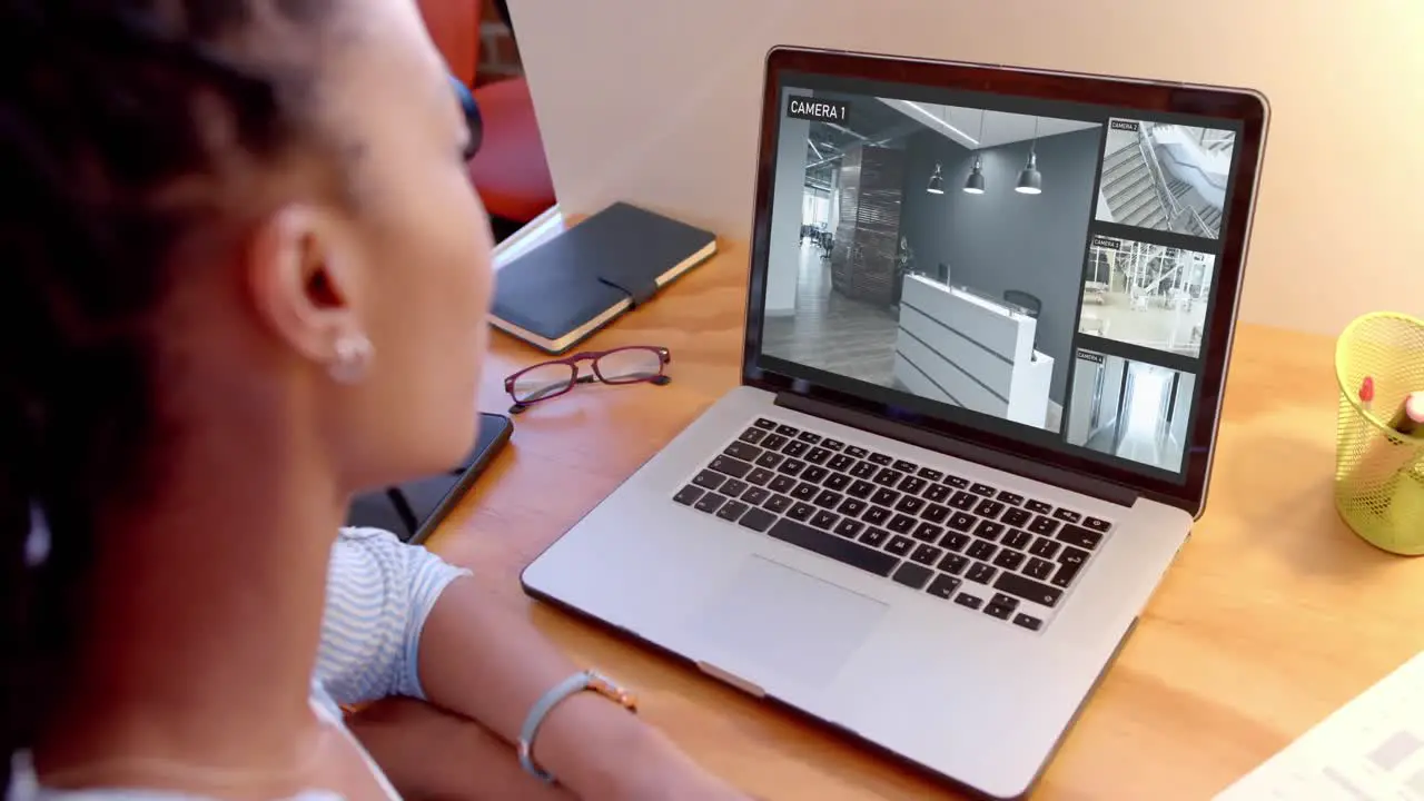 African american female security officer watching business cctv camera views on laptop slow motion