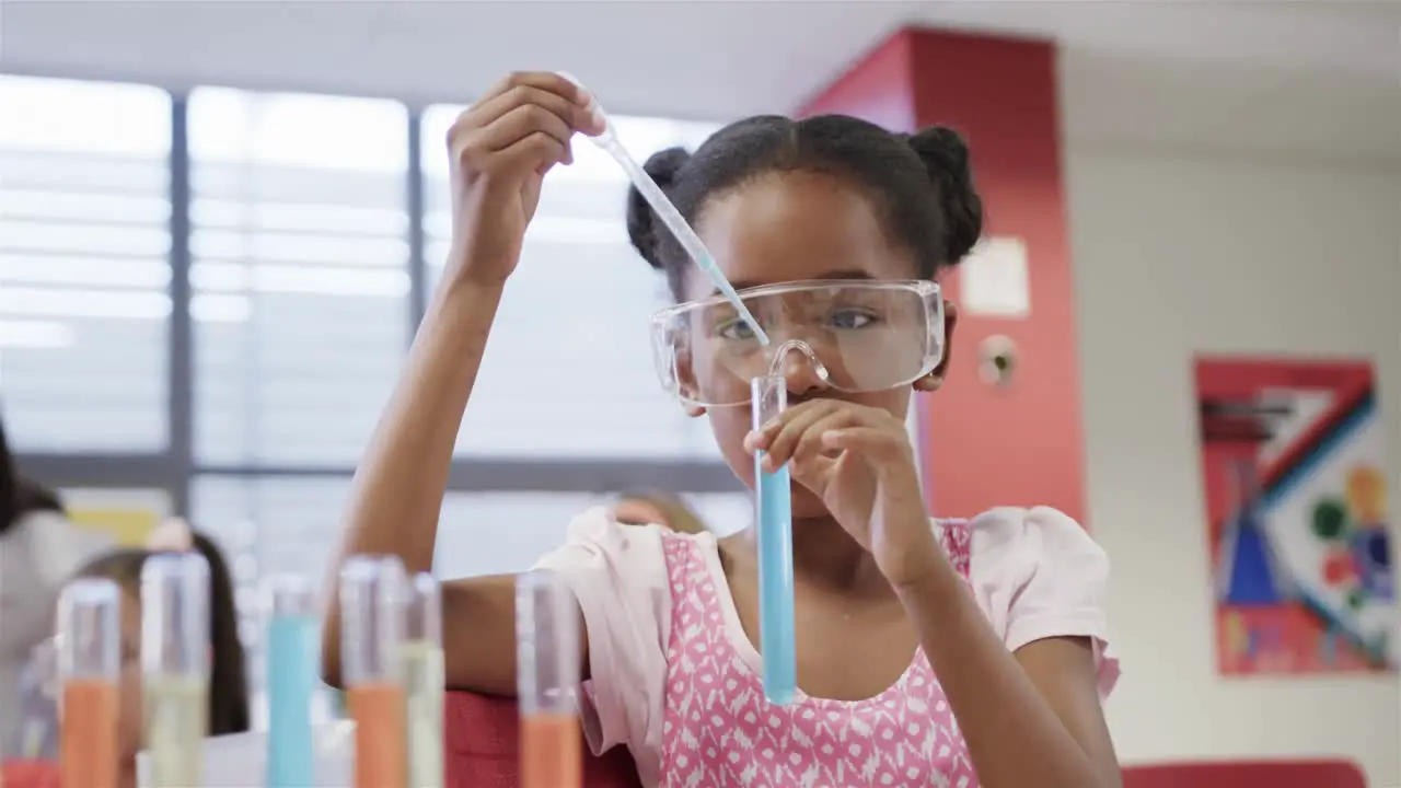 Focused african american elementary school schoolgirl with goggles in lab in slow motion