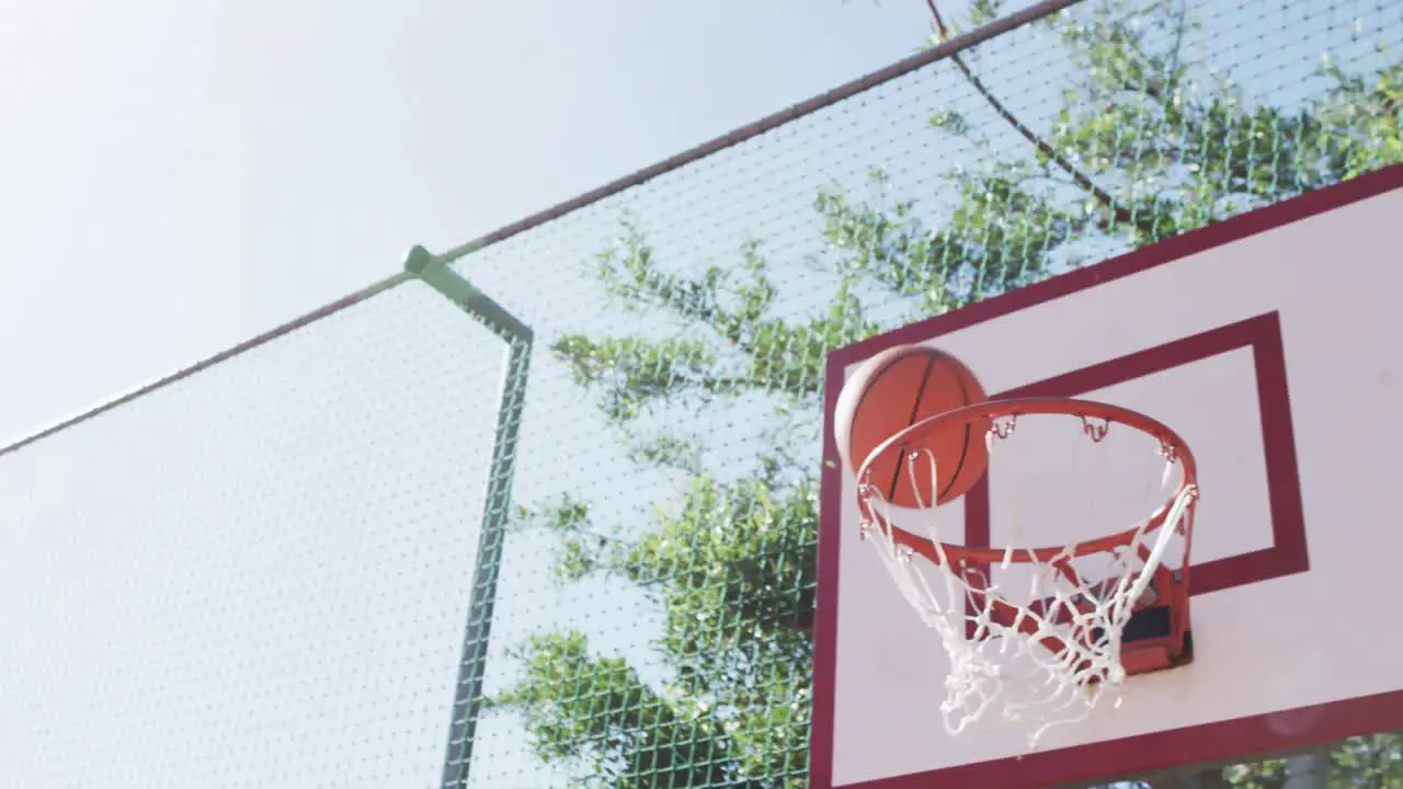 Flying ball on sunny basketball court in slow motion