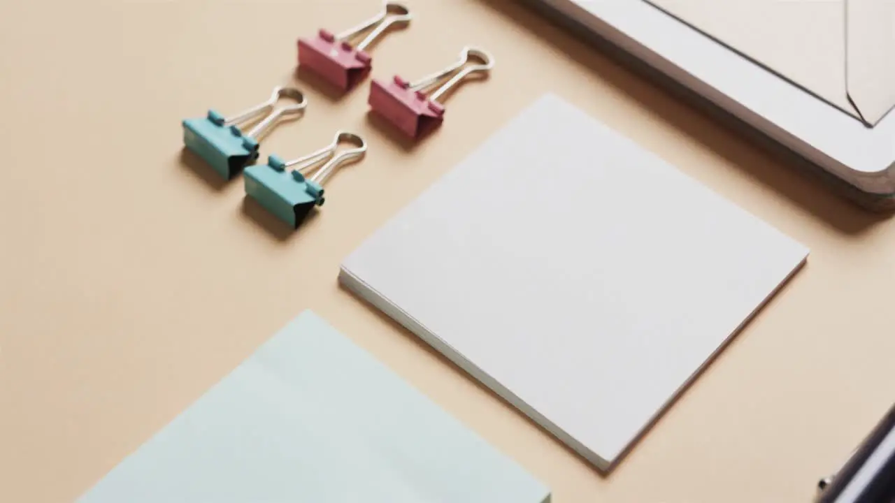 Close up of notebook pens and stationery arranged on beige background in slow motion