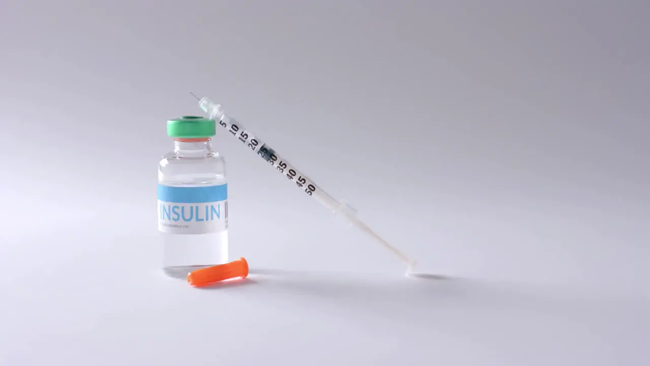 Close up of insulin vial and syringe on grey background slow motion