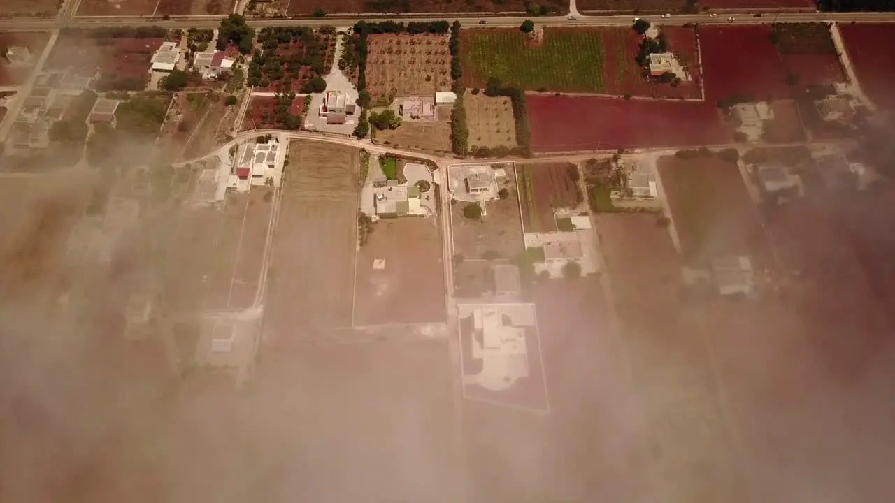 Static shot by drone of a colored field of puglia clouds are between the drone and the ground