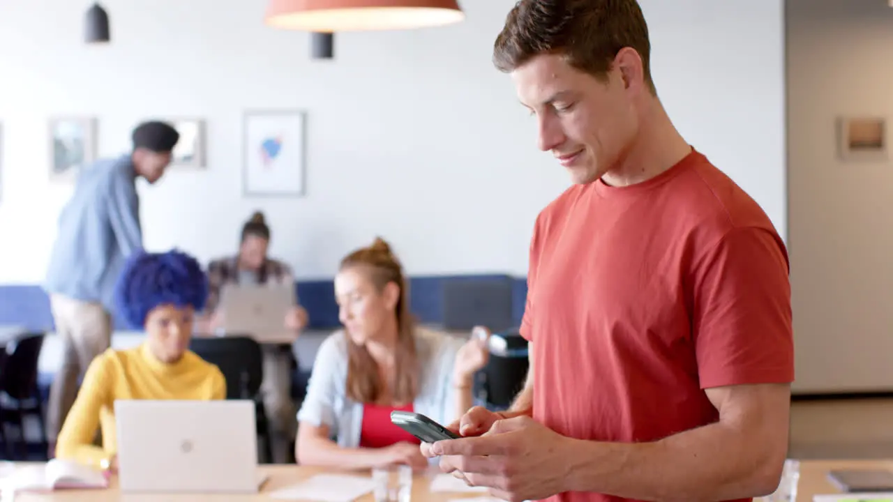 Portrait of happy caucasian casual businessman using smartphone in casual office slow motion