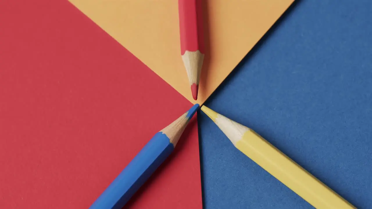 Overhead view of crayons on colourful background in slow motion