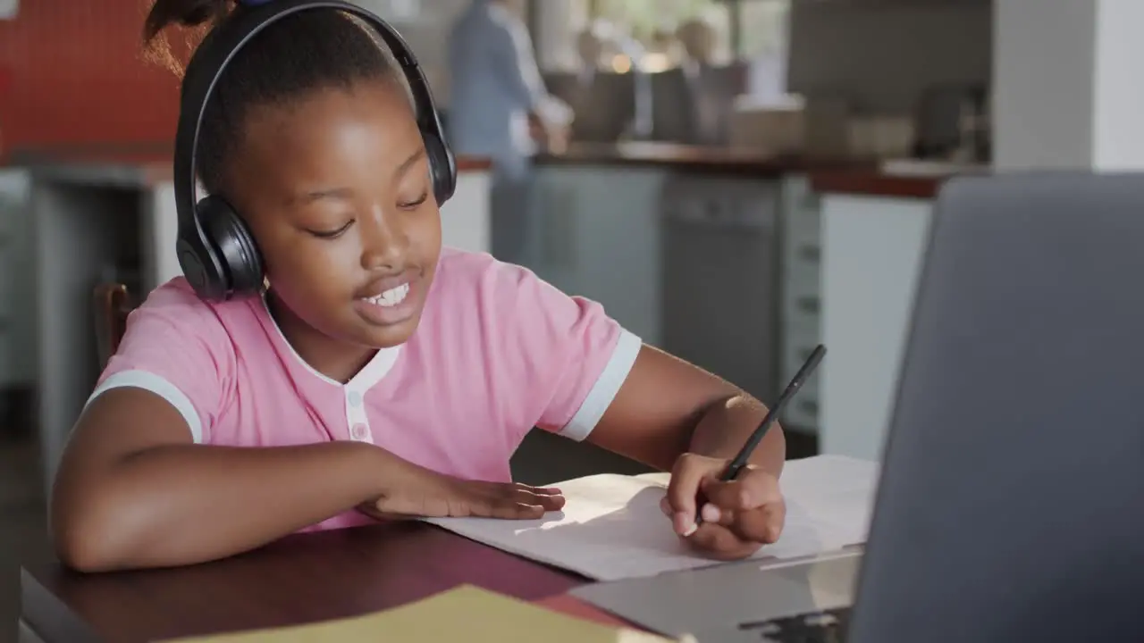 Happy diverse mother with daughter learning with laptop in kitchen in slow motion