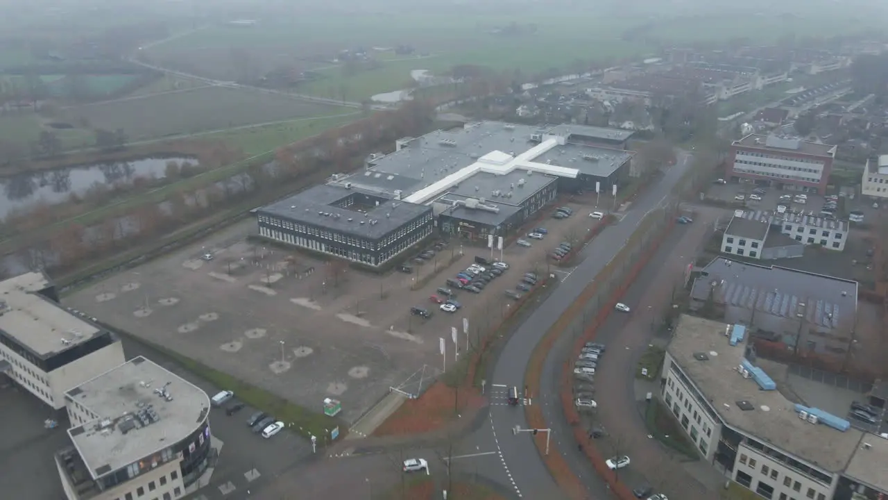 Aerial of office building on busy industrial terrain in foggy weather