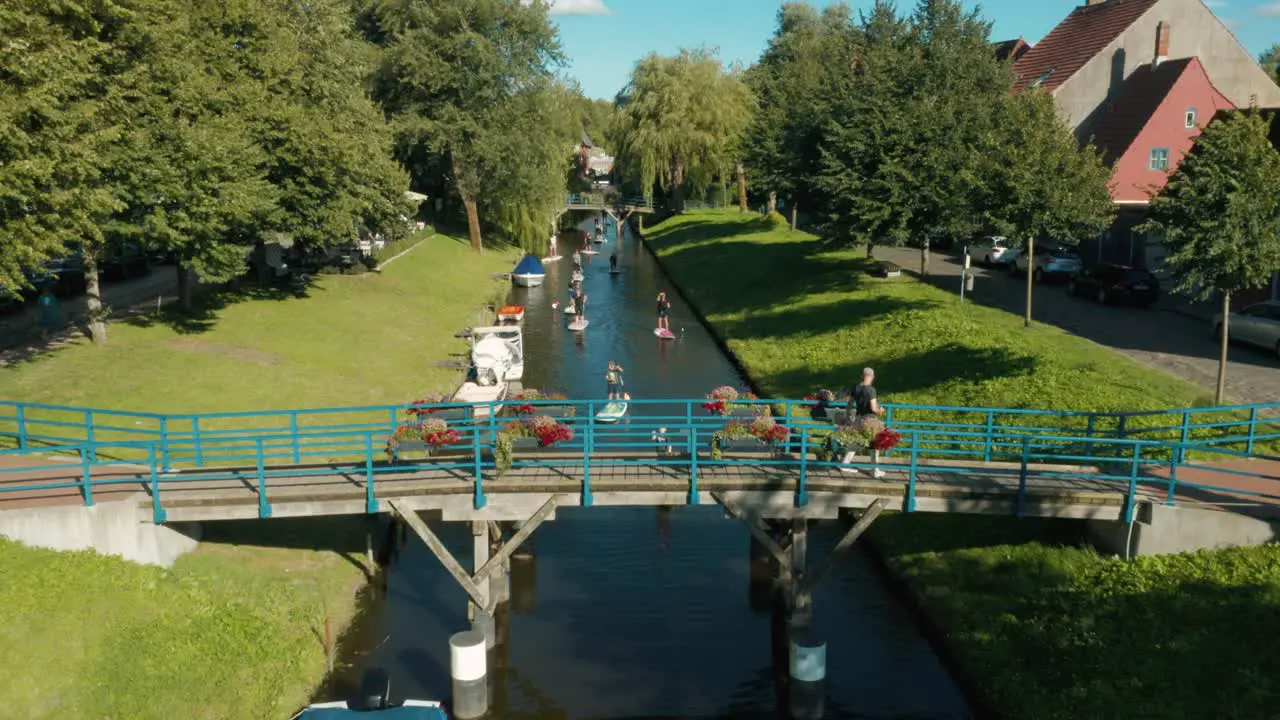 Tourists and locals enjoying Paddleboarding in canal on sunny summer vacation dolly out