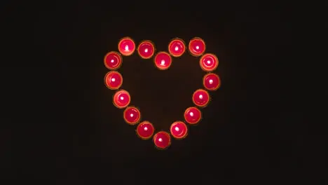 Overhead Shot Of Lit Red Candles In Shape Of Romantic Heart On Black Background