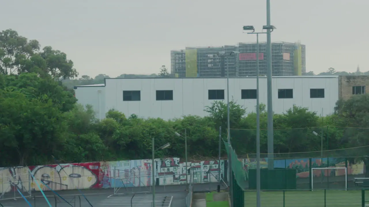 Filming out of a train window during the early dawn passing a sports complex and football soccer fields