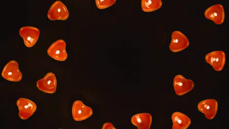 Overhead Shot Of Romantic Lit Heart Shaped Red Candles Revolving On Black Background With Copy Space