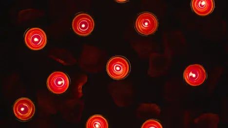 Overhead Shot Of Romantic Lit Red Candles Revolving On Background Covered In Rose Petals 1