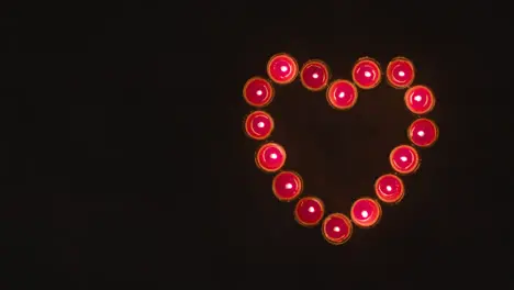 Overhead Shot Of Lit Red Candles In Shape Of Romantic Heart On Black Background 1